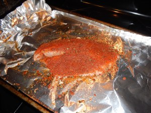 Raw tilapia prepared with spice mix on an oven sheet.